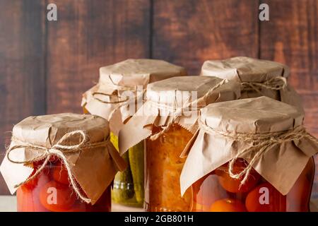 Vasetti di verdure fermentate su sfondo ligneo. Cetrioli in scatola fatti in casa, pomodori e crauti. Foto Stock