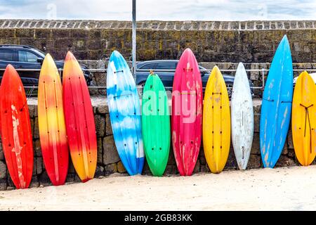 Tavole da surf colorate, canoe e kayak a Mousehole Harbour, Mousehole, Cornovaglia, Regno Unito Foto Stock