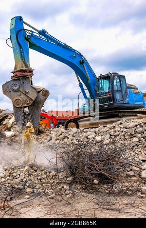 Escavatore da demolizione che separa ferri e calcestruzzo in cantiere - Abbruchbagger trennt Eisen und Beton auf Baustelle Foto Stock