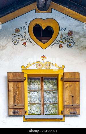 Finestra e decorazioni pittoresche di vecchia casa tradizionale a Evolene, un villaggio nella valle di Herens nella parte francofona del cantone Foto Stock