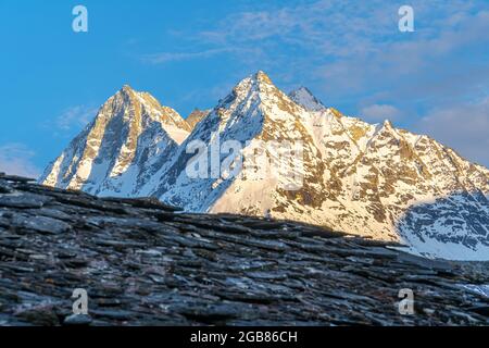 Paesaggio alpino montano sopra la Val Herens in Svizzera al tramonto con cime innevate e una nuvola molto grande Foto Stock