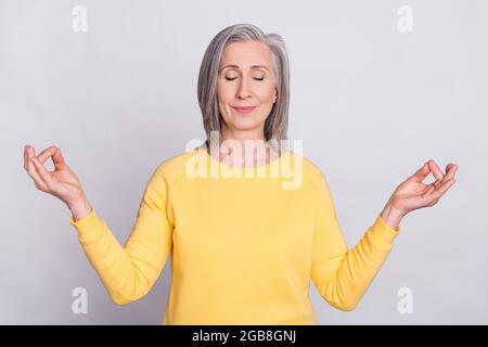 Foto di felice positivo buon umore sognante donna che medita yoga rilassante isolato su sfondo grigio Foto Stock