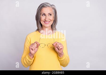 Foto di allegra sorridente bella donna matura guardare copyspace sognare pensare isolato su sfondo grigio colore Foto Stock