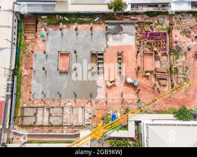 Vista aerea grande escavatore con camion in cemento su costruzione e lavoratore che versa un calcestruzzo bagnato in cantiere, costruzione di calcestruzzo Foto Stock