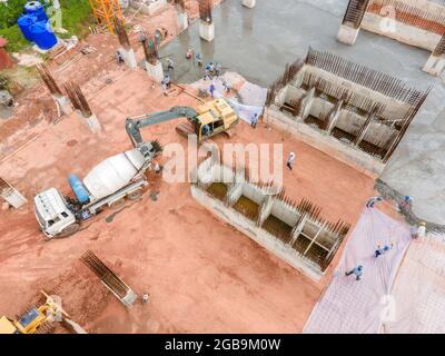 Vista aerea grande escavatore con camion in cemento su costruzione e lavoratore che versa un calcestruzzo bagnato in cantiere, costruzione di calcestruzzo Foto Stock