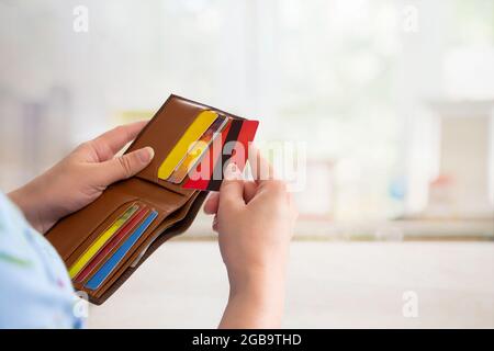 Donna che prende fuori le carte di credito e di debito dal suo portafoglio Foto Stock