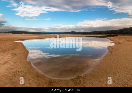 una vista di una spiaggia accanto ad un corpo d'acqua riflesso Foto Stock