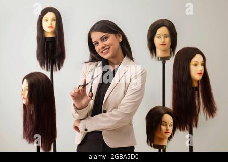 UNO STYLIST FELICE DEI CAPELLI CHE TIENE LE FORBICI IN MANO E IN POSA Foto Stock