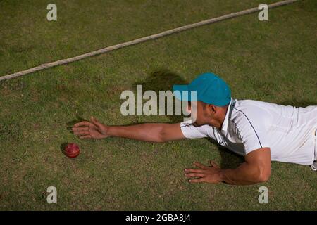 Un cricket fielder che incula la palla al boundry durante una partita Foto Stock