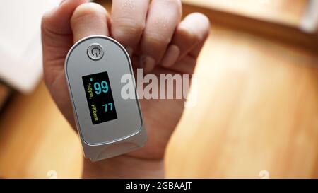 Pulsossimetro sul dito che indica la saturazione dell'ossigeno e la frequenza cardiaca. Prevenzione dell'ipossia in polmonite Foto Stock