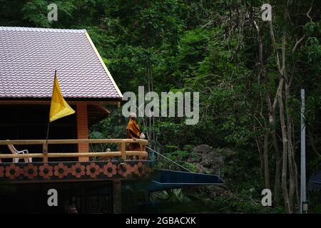 Un monaco buddista osserva una foresta dal piano superiore della sua residenza Foto Stock