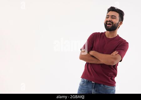 UN UOMO BEARDED IN PIEDI CON LE MANI INCROCIATE E RIDENTI Foto Stock