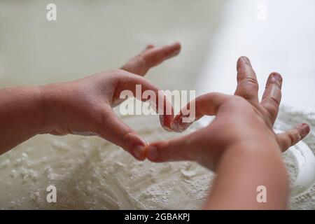 Sfondo in forno a forma di cuore fatto di farina e mani di capretto. Vista dall'alto. Concetto di amore per la famiglia. Pasqua, Natale, Festa della mamma, Capodanno panificazione concep Foto Stock