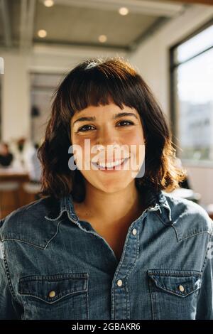 Ritratto di felice esecutivo femminile in ufficio. Donna d'affari allegra nello spazio di co-working. Foto Stock