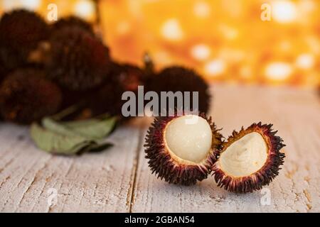 Primo piano di un pulasan pelato. Pulasan è un frutto tropicale della famiglia dei frutti di bosco, simile al rambutan. Messa a fuoco selettiva. Sfondo sfocato Foto Stock