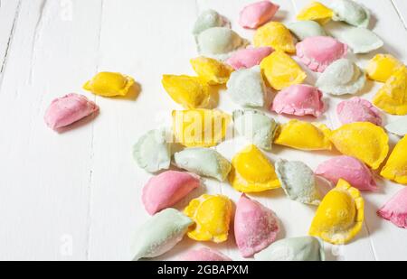 set di coloratissimi gnocchi per bambini di pasta colorata ripiena di carne su sfondo bianco di legno Foto Stock