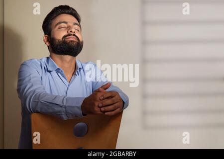 UN GIOVANE UOMO SOPPORTATO SEDUTO DA SOLO E PENSANDO Foto Stock