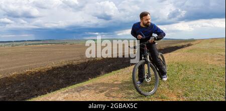 Panorama ciclista da braccio su una mountain bike in un campo Foto Stock