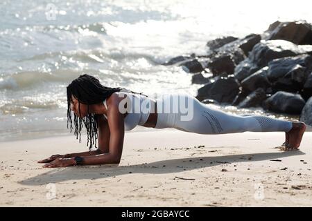 Giovane donna in forte forma in posizione a tavola sulla spiaggia di sabbia Foto Stock