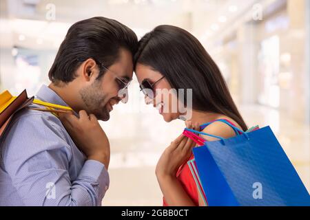 Un giovane uomo e una donna che portano borse da shopping in piedi con la fronte toccata. Foto Stock