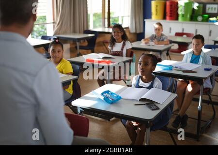 Vista posteriore del gruppo di insegnanti maschi caucasici di diversi studenti della classe a scuola Foto Stock