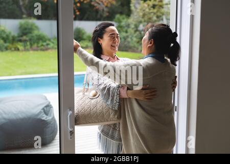 Felice anziana donna in casa con figlia adulta abbracciando Foto Stock