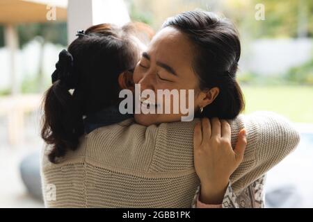 Felice anziana donna in casa con figlia adulta abbracciando Foto Stock