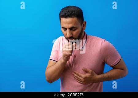 Giovane arabo che si sente malato e tosse su sfondo blu Foto Stock