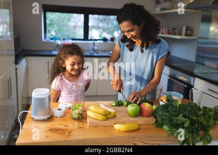 Felice gara mista madre e figlia che cucinano insieme in cucina Foto Stock