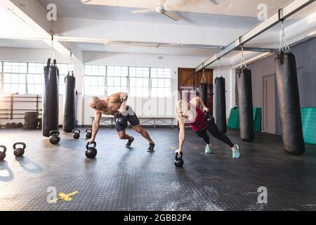 Uomo caucasico e donna che si esercitano in palestra, facendo spingere su utilizzando i pesi Foto Stock