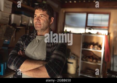 Tagliatrice maschio caucasica con mani incrociate in officina Foto Stock