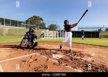 Gruppo vario di giocatori femminili di baseball in azione sul soleggiato campo da baseball durante la partita Foto Stock