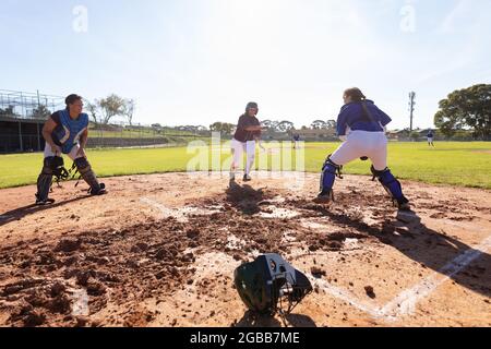 Gruppo vario di giocatori femminili di baseball in azione sul soleggiato campo da baseball durante la partita Foto Stock