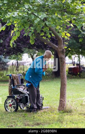 Un uomo di 86 anni fa Falun Gong esercizi lenti vicino ad un albero. A Queens, New York, un posto molto diverso. Foto Stock