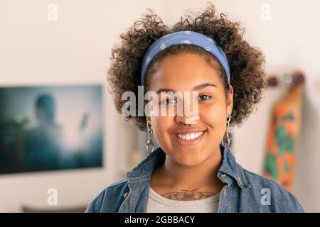 Allegra ragazza adolescente in casualwear guardando con sorriso in ambiente domestico Foto Stock