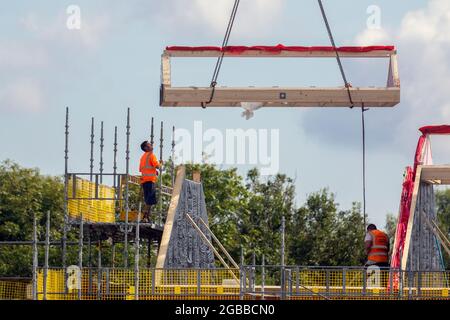 Keepmoat case sviluppatori di proprietà; fasi di costruzione nel sito di sviluppo a Chorley. Costruttori iniziare la costruzione su questa grande nuova tenuta di case; tetti legno stecche dormer, bordo di cresta, travi e costruzione dormitori, membri del tetto, guancia bordo asse di legno soffit telaio e rivestimenti apex tetto in legno. Tetto spiovente dormitorio costruire su campo verde estate. Foto Stock