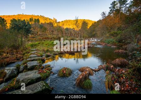 Mestres Weir sul sentiero di Piscarido e paesaggio autunnale con il fiume Cabril al tramonto a Mondim de basso, Norte, Portogallo, Europa Foto Stock