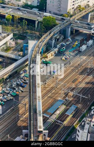 tokyo, giappone - aprile 25 2021: Vista dall'alto di un treno Yamanote Line sulle tracce della stazione Hamamatsucho sovrastata dall'aereo Tokyo Monora Foto Stock