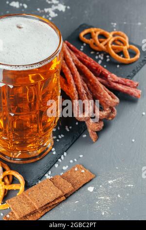 set di birre e appetitosi spuntini da birra. Tavolo con mug di birra, tavola di legno con salsicce Foto Stock