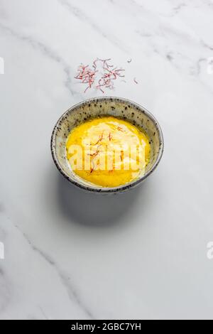 Salsa di rouille con fili di zafferano trefoli su sfondo bianco di marmo con pacchetto di zafferano in background – FOODPIX BIANCO Foto Stock