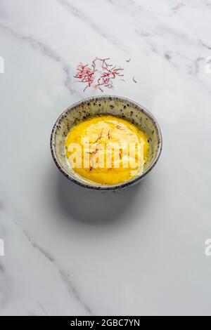 Rouille con fili di zafferano trefoli su marmo Bianco di fondo con confezione di zafferano sullo sfondo – FOODPIX BIANCO Foto Stock