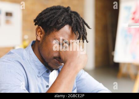 Stanco pittore afroamericano maschile al lavoro in studio d'arte Foto Stock