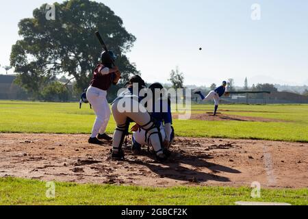 Gruppo vario di giocatori femminili di baseball in azione sul soleggiato campo da baseball durante la partita Foto Stock