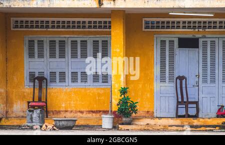 Nha Trang, Khanh Hoa Provincia, Vietnam - 4 gennaio 2019: La facciata della casa è gialla con persiane chiuse in legno sulle finestre. Ci sono chai Foto Stock