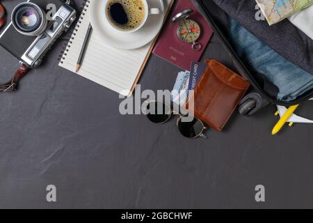 Prepara una valigia, una macchina fotografica vintage, un notebook, un passaporto, una mappa e un caffè caldo sul pavimento in piastrelle nere e sullo spazio per la copia. Concetto di viaggio Foto Stock