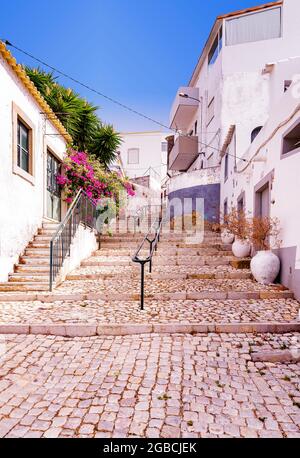 Tipico Algarve ripida strada laterale percorso a piedi lastricato con tradizionali ciottoli portoghesi o calcada. Estoi Algarve Portogallo Foto Stock