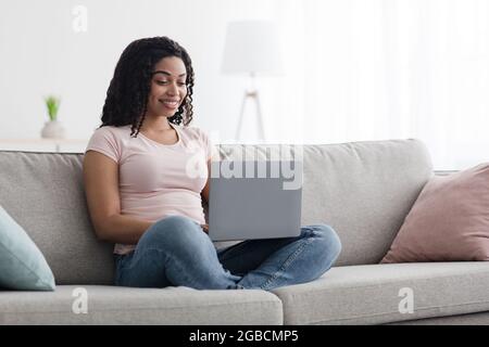 Piacevole giovane e felice freelance che lavora sul computer a casa Foto Stock