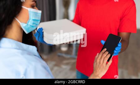 Cliente in maschera di protezione ricezione firma ordine modulo di prova digitale Foto Stock