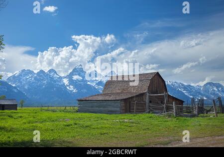 Vecchio fienile in un campo sotto le montagne del Grand Teton con le nuvole drammatiche in un pomeriggio di sole Foto Stock