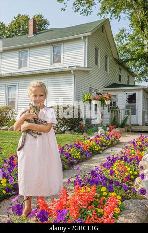 Indiana Shipshewana, Amish Farm Tour, ragazza bambino tiene casa kitten in piedi davanti all'esterno, Foto Stock